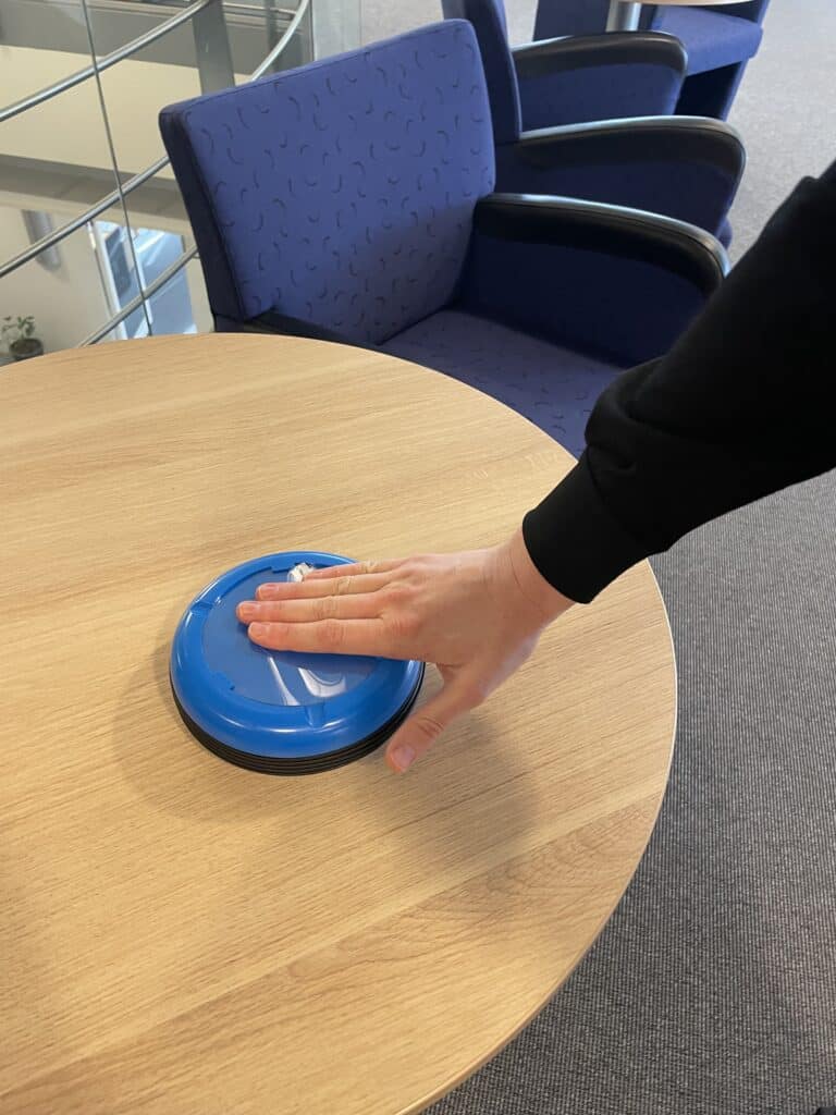 En person som trycker med handen på en stor blå knapp.