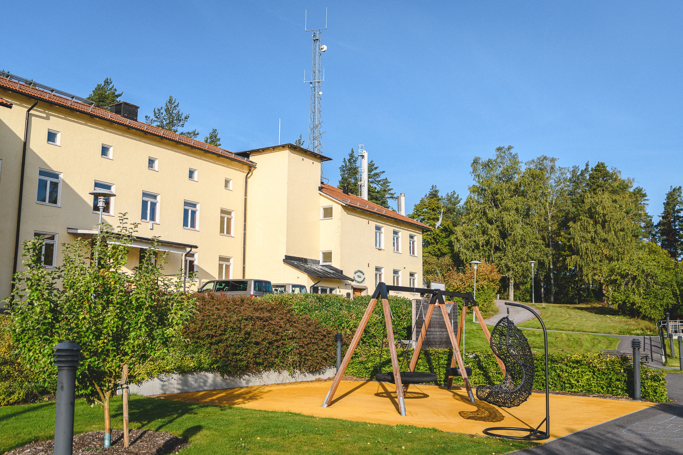 Gungställning och grönt gräs på gården utanför skolan