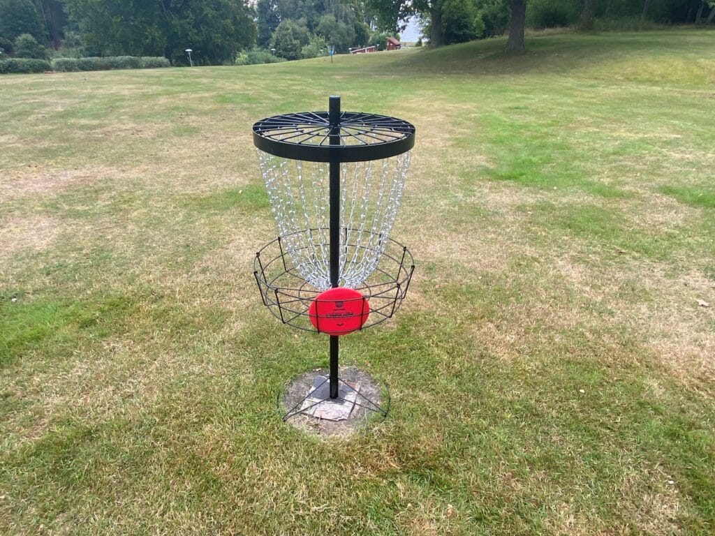 En discgolfs-korg med en röd disc i.