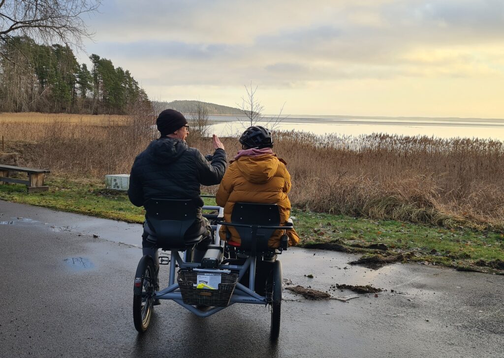Två personer på en side-by-side-cykel som tittar ut över en sjö.