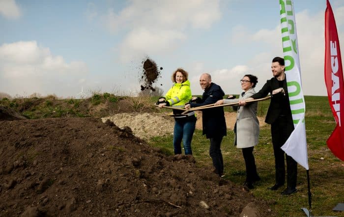 Fyra personer står på rad bredvid varandra och tar ett spadtag och kastar upp jord i luften