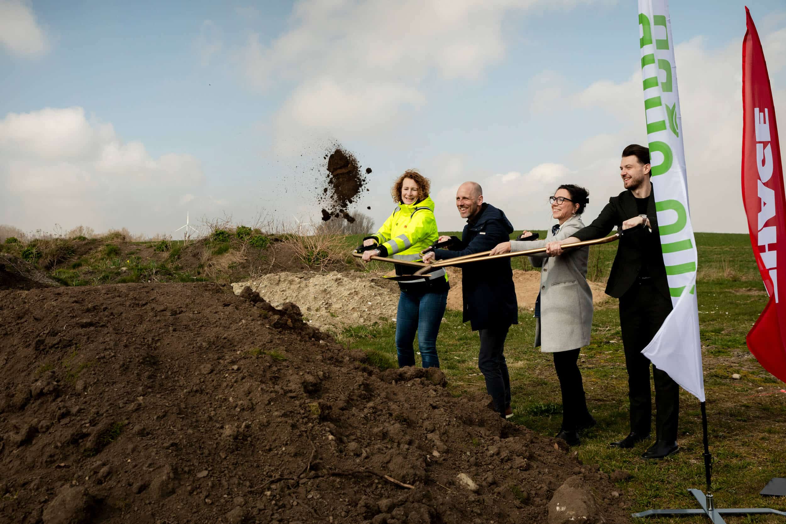 Fyra personer står på rad bredvid varandra och tar ett spadtag och kastar upp jord i luften